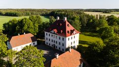 Puutarhojen ympäröimä Louhisaaren kartanolinna aurinkoisena päivänä.