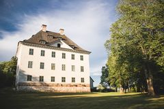 Valkoinen kartanorakennus vehreässä puistossa.