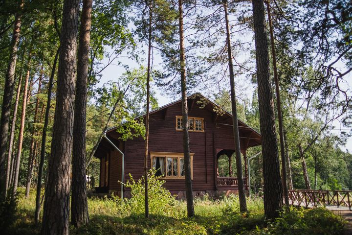 Punainen%20puurakennus%20mets%E4isell%E4%20alueella%2C%20puiden%20keskell%E4.