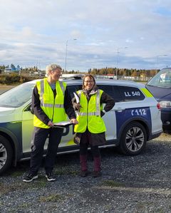 Kaksi eläinlääkäriä seisoo poliisiauton edessä.