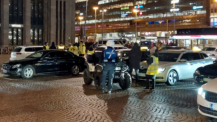 Valvontaviranomaisia ja takseja Helsingin rautatieaseman edustalla illalla.