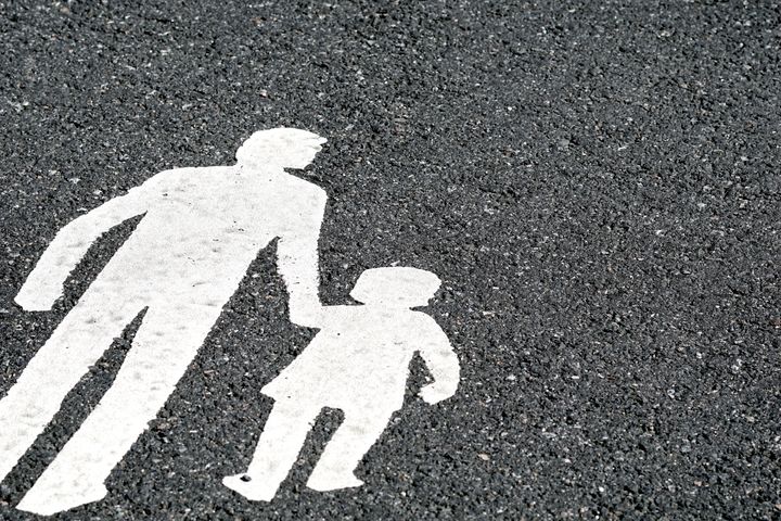 Kuva jalkakäytävän maalauksesta, jossa aikuinen ja lapsi kävelevät suojatiellä.