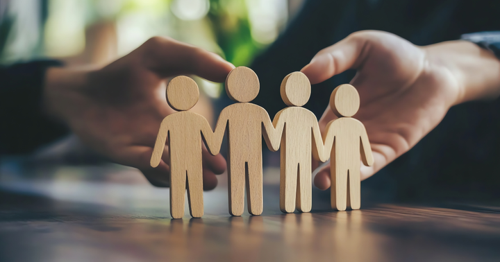 Träfigurer på ett bord håller varandra i händer.