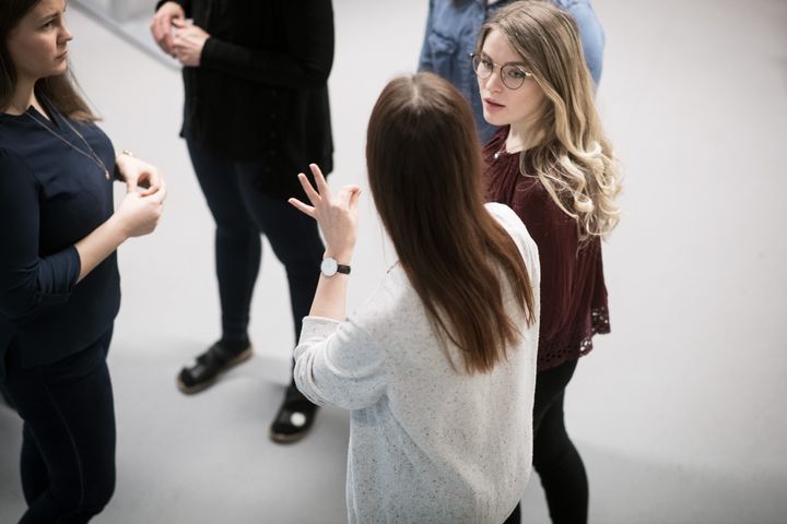 Tulkkausopiskelijoita keskustelemassa viittomia hyödyntäen.