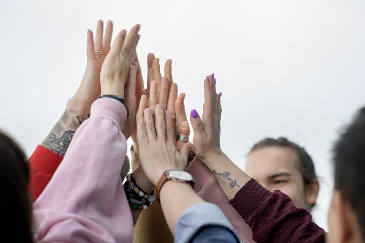 Useiden henkilöiden kädet yhdessä ilmassa, symboloiden yhteisöllisyyttä.