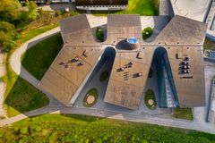 Ilmakuva modernista arkkitehtonisesta Tampereen Tipotien terveysasemasta, jossa on epäsymmetrinen katto ja ympärillä kävelypolkuja ja vihreää nurmikkoa.