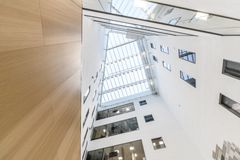 Kuvituskuvassa on näkymä modernin rakennuksen kerroksista alhaalta ylöspäin kirkkaasti valaistuun kattorakenteeseen.