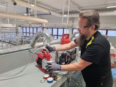 Kouluttaja työskentelee teollisuuskeittiön kylmälaitteiden parissa valoisassa harjoitustilassa.