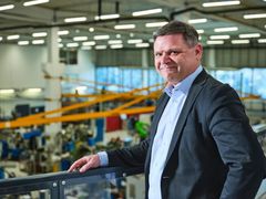 Jarno Tuimala nojaa kaiteeseen, taustalla näkyy koneistushalli.