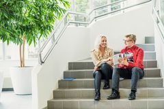 Kaksi henkilöä istuu portailla, katsoen kirjaa yhdessä.