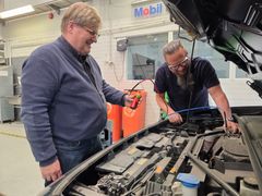 Juha Vainio ja Mika Sivenius kytkemässä hiilidioksidi-ilmastointihuoltolaitetta auton ilmastointilaitteeseen.