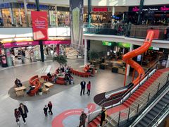 Kauppakeskus Myllyn yläkerrasta otettu kuva, jossa näkyy alakerrassa oleva Myllyntori, liukumäki, ihmisiä ja kauppakeskuksen liikkeitä.