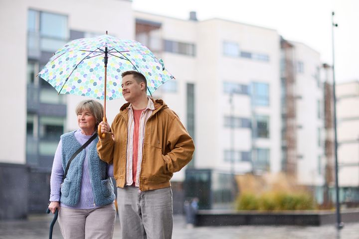 Två personer som går under ett paraply i stadsmiljö.