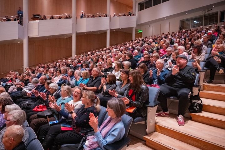 Ihmiset istuvat teatterisalissa ja taputtavat esityksen aikana.