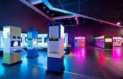 Interaktiivinen näyttelytila, jossa on erilaisia valaistuja näyttöjä ja värikkäitä pelinäyttelyitä.