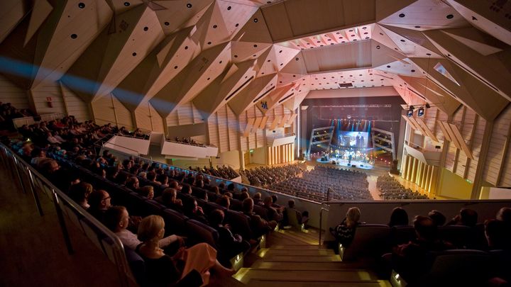 Konserttisali, jossa suuri yleisö katselee lavan esitystä.