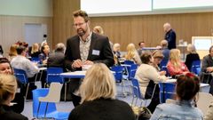 Kuva seminaarista, jossa osallistujat keskustelevat ryhmissä pöytien äärellä.