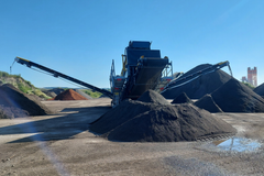 Kuva hiekoitushiekan seulontalaitteesta kiertotalousalueella, ympärillä hiekkakasoja.