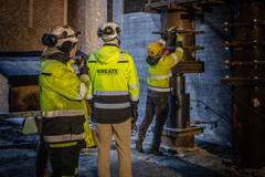 Kolme henkilöä työskentelee tunkatun Ratapihankadun sillan luona yöllä, keltaisissa heijastintakeissa ja kypärissä.