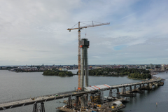 Ilmakuva Kruunuvuorensillasta syyskuussa 2024. Keskiössä on korkea, rakenteilla oleva pyloni nosturin vieressä.