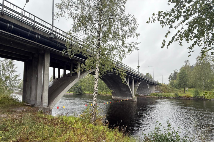 Vanha silta joen yli vehreässä ympäristössä.
