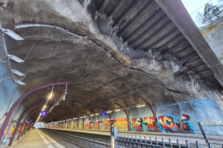 Kuva Helsingin Malminkartanon juna-asemasta tunnelissa. Näkyvissä on laitureita, graffitilla koristeltuja seiniä ja tunnelin kaareva katto.