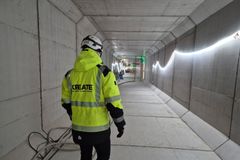 Työmaata helpottava tekninen tunneli, henkilö kulkee keltaisessa turvatakissa.