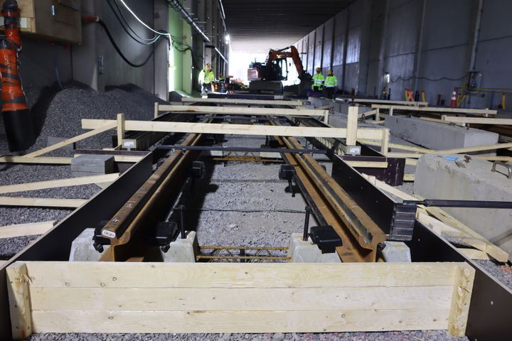 Valokuva näyttää rakennustyömaan, jossa etualalla ovat irtokiinnikkeet asennettuina betonialustalle. Taustalla kirkkaita valoja ja työkoneita.