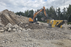 Kaivinkone syöttää purkubetonia murskaimeen työmaalla, jossa betonijäte jalostetaan betonimurskeeksi.