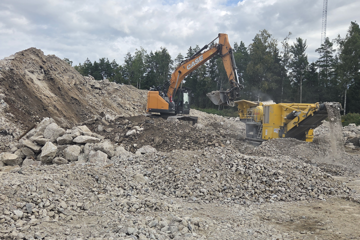 Kaivinkone syöttää purkubetonia murskaimeen työmaalla, jossa betonijäte jalostetaan betonimurskeeksi.
