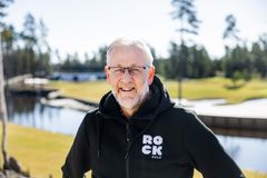 Vanhempi mies ulkona golfkentällä, taustalla puita ja pieni lampi.