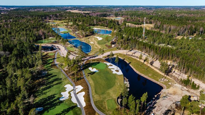 Ilmakuva yhdeksänreikäisestä golfkentästä, jossa on vihreitä väyliä, hiekkabunkkereita ja vesialtaita.