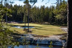 Golfkenttä metsäisellä alueella, jossa on viheriö ja hiekkabunkkereita.