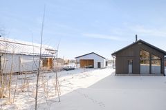 Rakenteilla olevia pientaloja aurinkoisessa talvisäässä lumen keskellä.