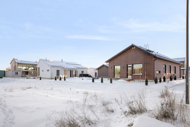 Rakenteilla olevia pientaloja lumisessa maisemassa.