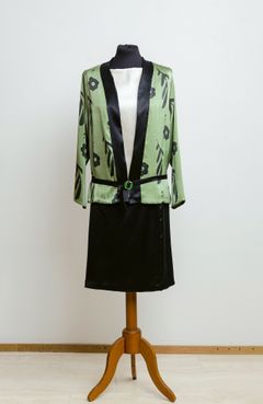 Vaatesuunnittelija-ompelija Irma Romeron tulkinta mallin asusta Helene Schjerfbeckin maalauksessa Tumma nainen (1929). Kimono­tyyliset takit ja vekkihameet olivat muotia 1920-luvulla. Kukkakuosi on käsinmaalattu oliivinvihreäksi värjätylle kreppisilkille.