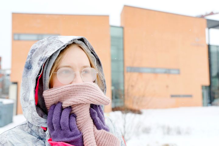 Kuvassa talvisesti pukeutunut henkilö ulkona, jonka suun peittää huivi ja silmälasit ovat huurussa.