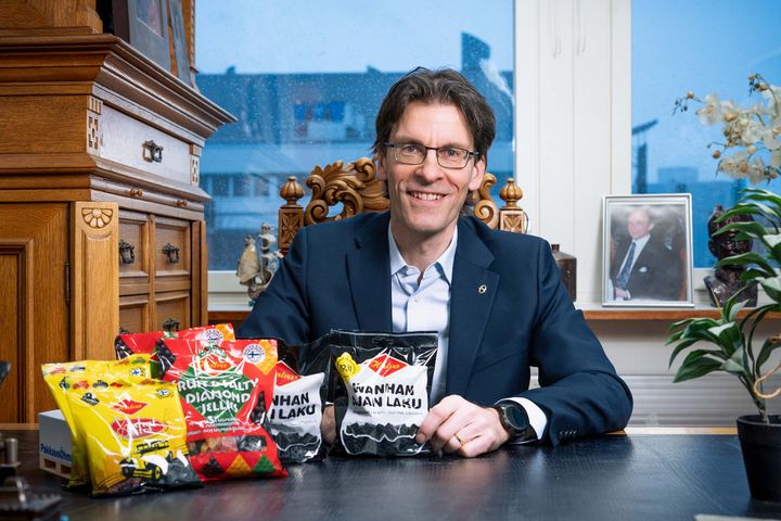 Jean Karavokyros istuu pöydän ääressä, edessään makeispusseja.