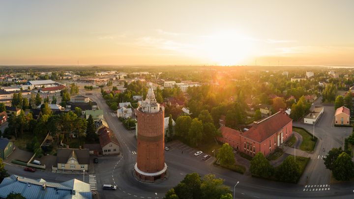 Kokkolan vanha vesitorni auringon noustessa. Taustalla näkyy kaupungin silhuettia