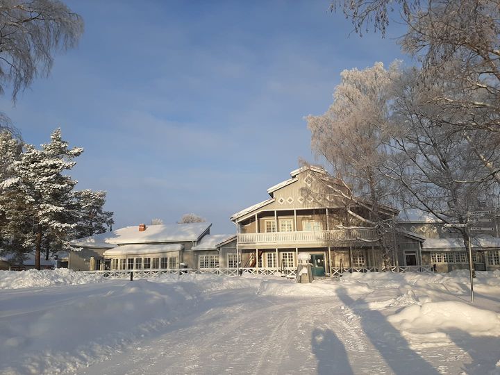 Talviaurinko paistaa valkoiselle lumelle. Taustalla näkyy nuorisokeskus Villa Elban päärakennus.