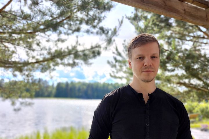 Mies seisoo järvimaiseman edessä.