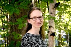 Henkilö seisoo metsässä, taustalla vihreitä lehtiä ja puita.