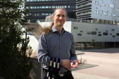 Henkilö seisoo ulkona modernin rakennuksen edessä ja pitelee käsissään kuivaelektrodeja.