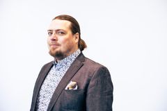 Mies puvussa ja kuviollisessa kauluspaidassa valkoista taustaa vasten.