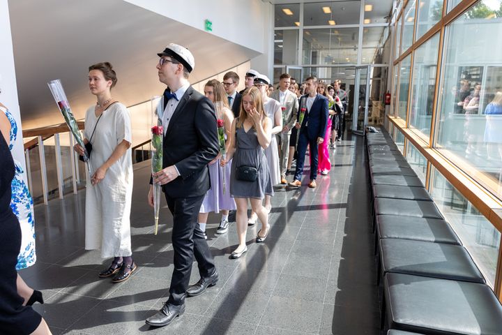 Ryhmä ihmisiä kävelee sisätiloissa kevätjuhlassa.