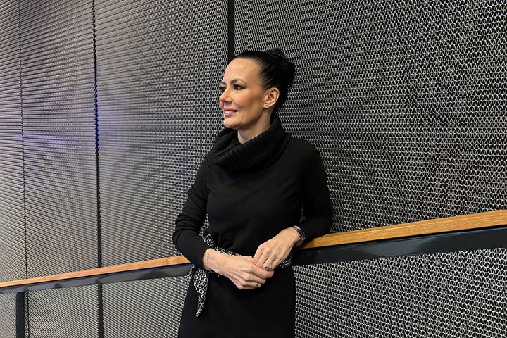 Henkilö seisoo metalliverkkoa vasten, pukeutuneena mustaan puseroon.