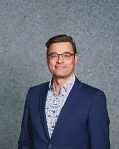 Harri Haapasalo sinisessä pikkutakissa katsoo kameraan.