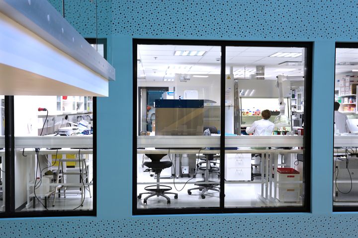 Laboratorio, jossa on lasiseinä ja henkilö työskentelee tietokoneen ääressä.