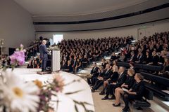 Täpötäysi juhlasali, jossa lääketieteen lisensiaatit valmistujaisjuhlassa. Puhuja seisoo puhujakorokkeella.