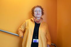Päivi Vartiainen oranssin seinän edustalla TAMKin tiloissa.